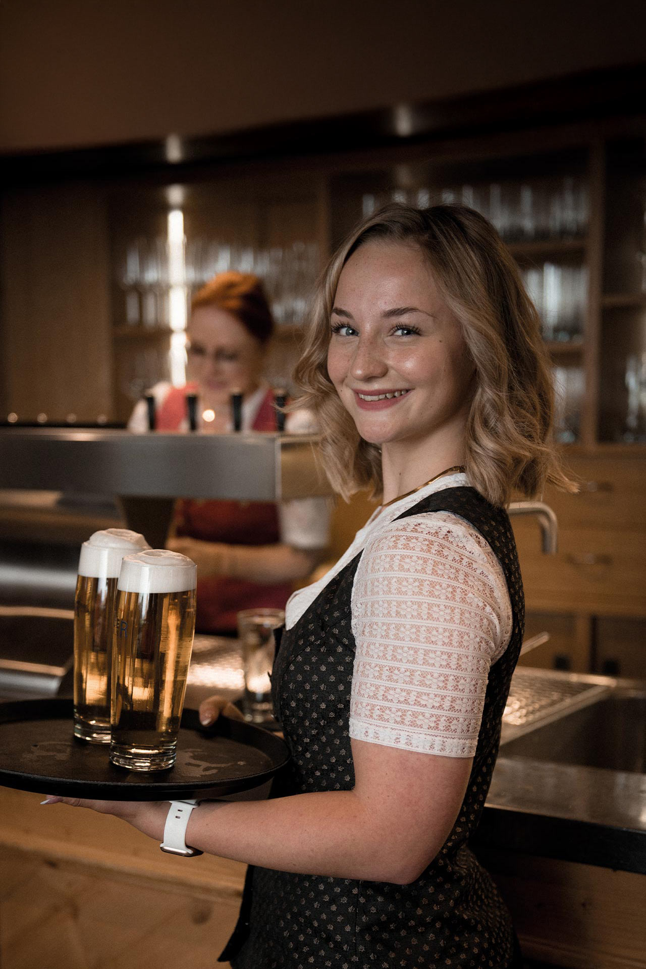 Eine junge Kellnerin lächelt in die Kamera